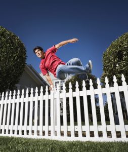 man jumping over fence